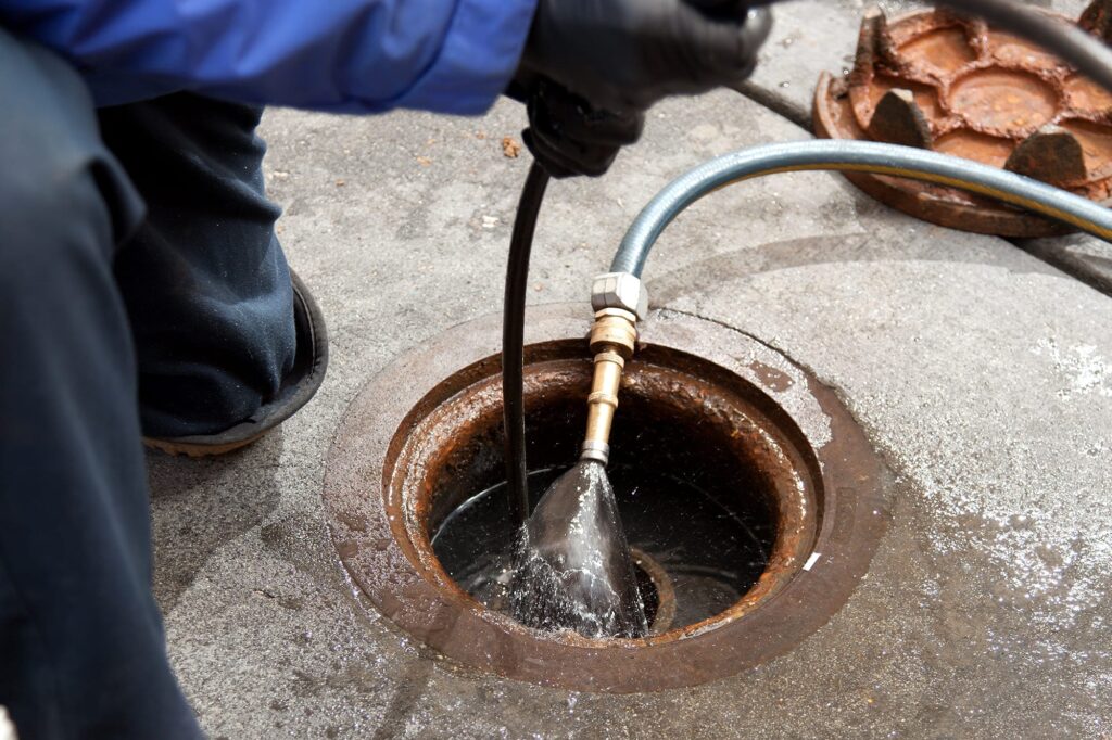 Plumber hydro jetting a sewer line through a manhole in Jacksonville Beach
