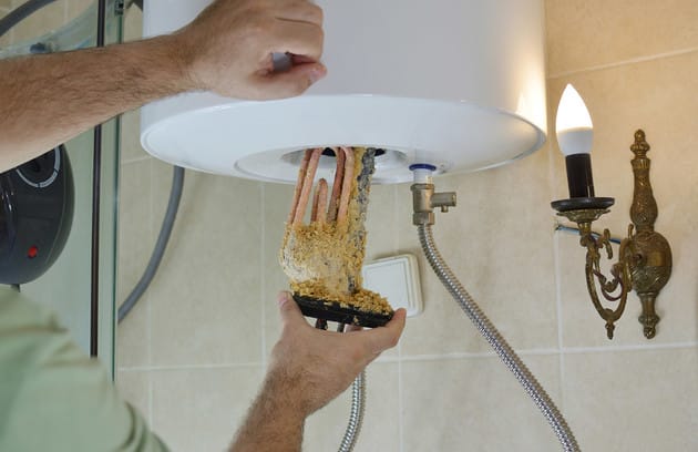 Technician removing mineral buildup from a water heater in Jacksonville Beach